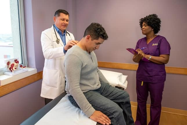 AICA doctor and nurse examining patient back and neck injury on table